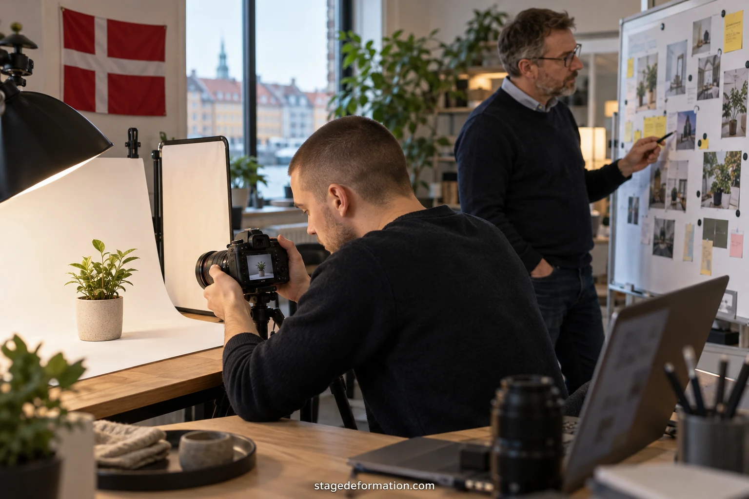 To praktikanter forbereder en kampagnepræsentation foran en tavle med post-it-sedler i et bureau i København